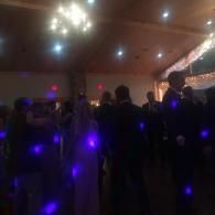 People dancing in a dimly lit ballroom with purple lights and a decorated ceiling