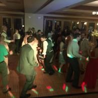 People dancing in a dimly lit indoor hall with colorful floor lights
