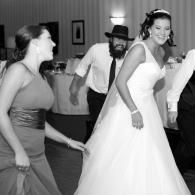 Bride dancing at a wedding reception with two guests in formal attire