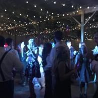 People dancing under string lights at a nighttime outdoor party