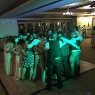 People dancing in a group under green lighting at an indoor event