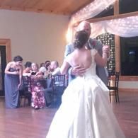Bride and groom slow dancing at a wedding reception with guests seated nearby