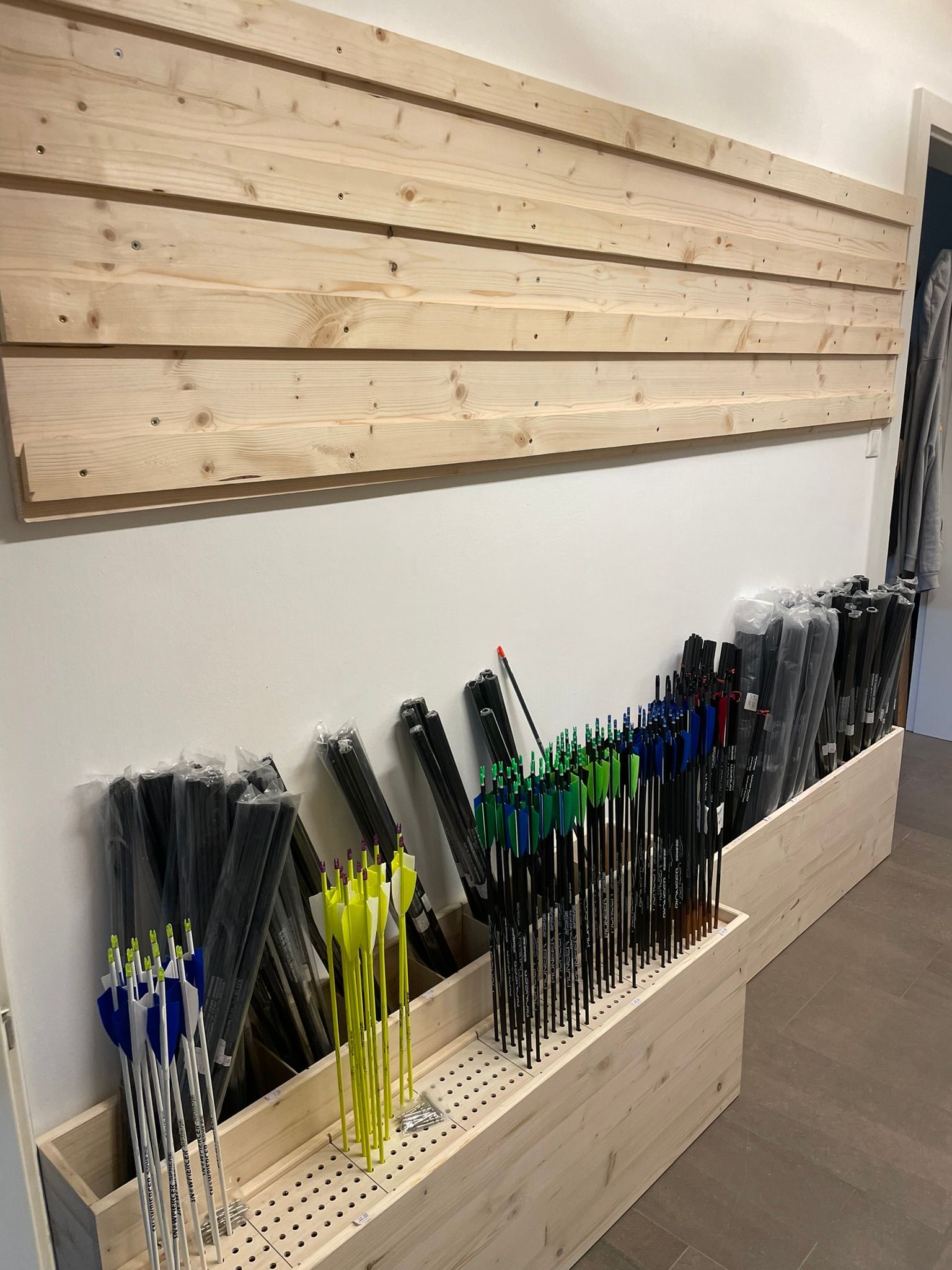 Ein Bündel Pfeile sind auf einem Holzregal aufgereiht