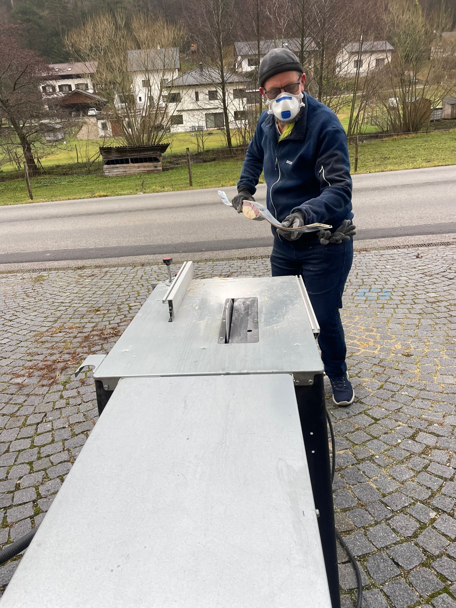 Ein Mann mit Maske arbeitet an einer Tischkreissäge