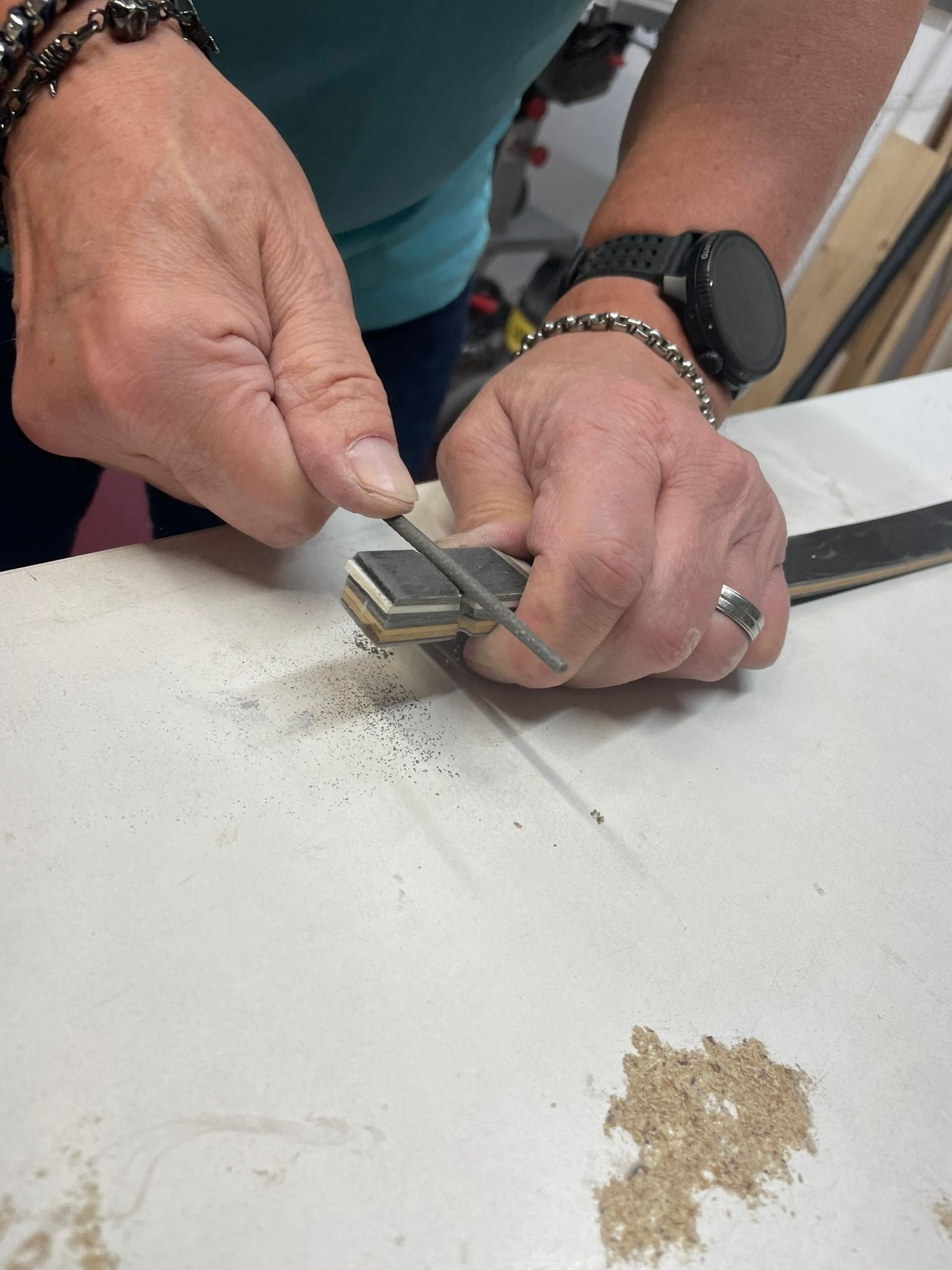 Ein Mann mit einer Uhr feilt an einem Stück Holz