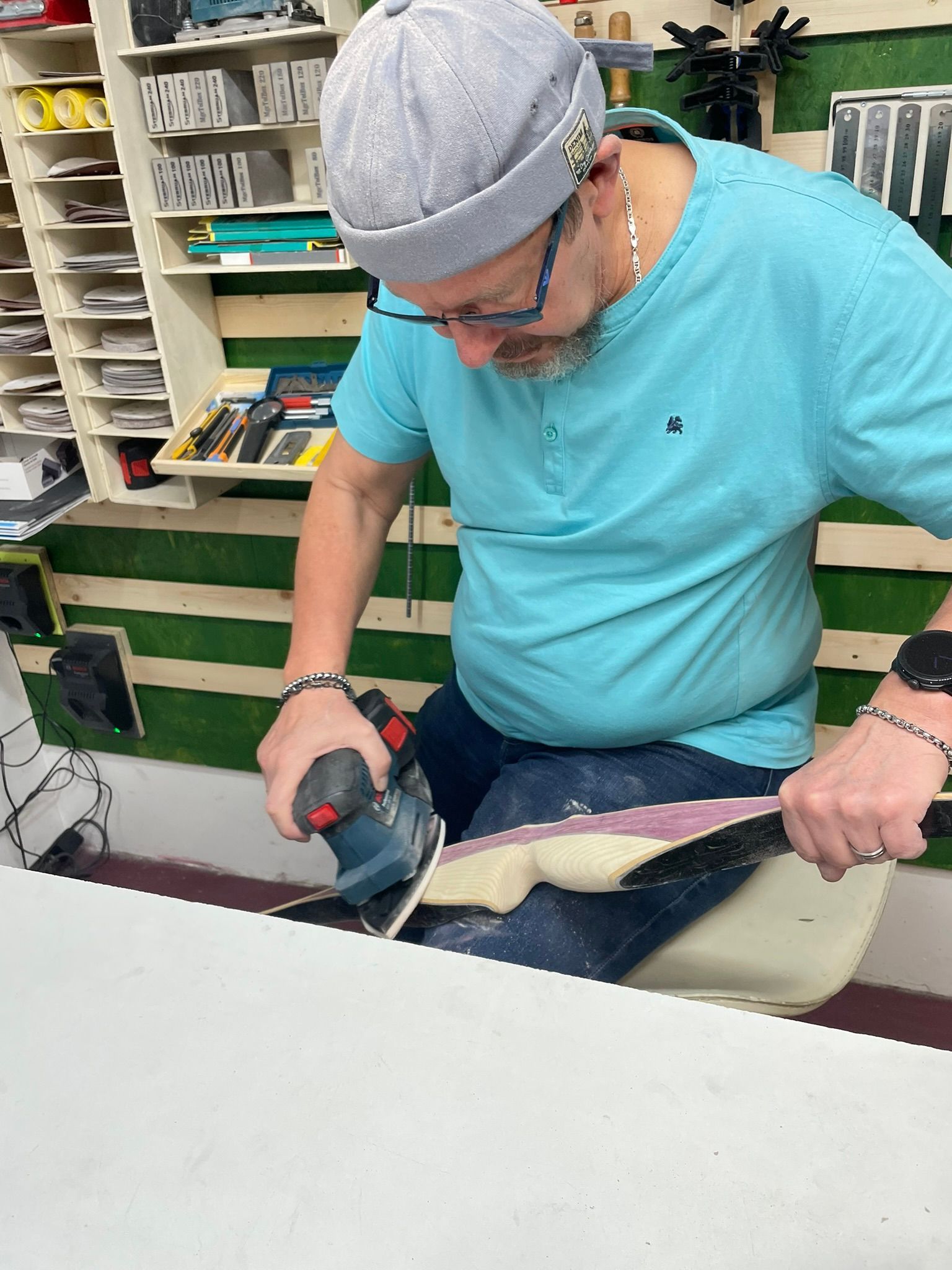 Ein Mann im blauen Hemd schleift ein Stück Holz