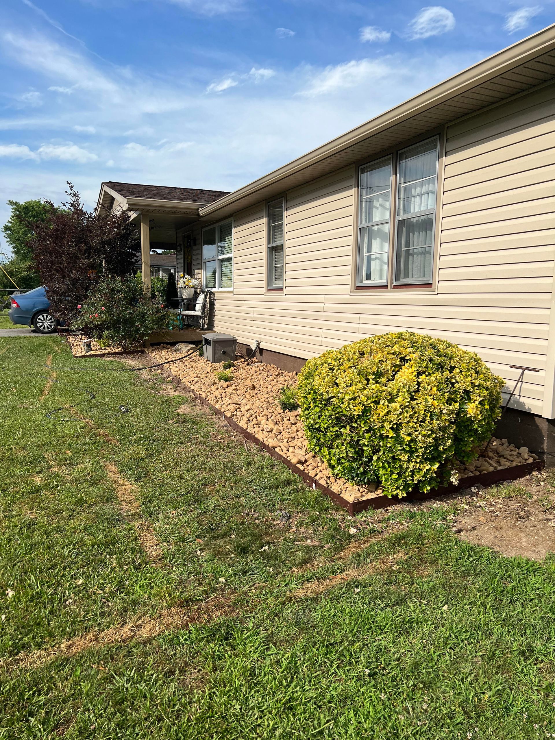 A house with a lot of grass and bushes in front of it.