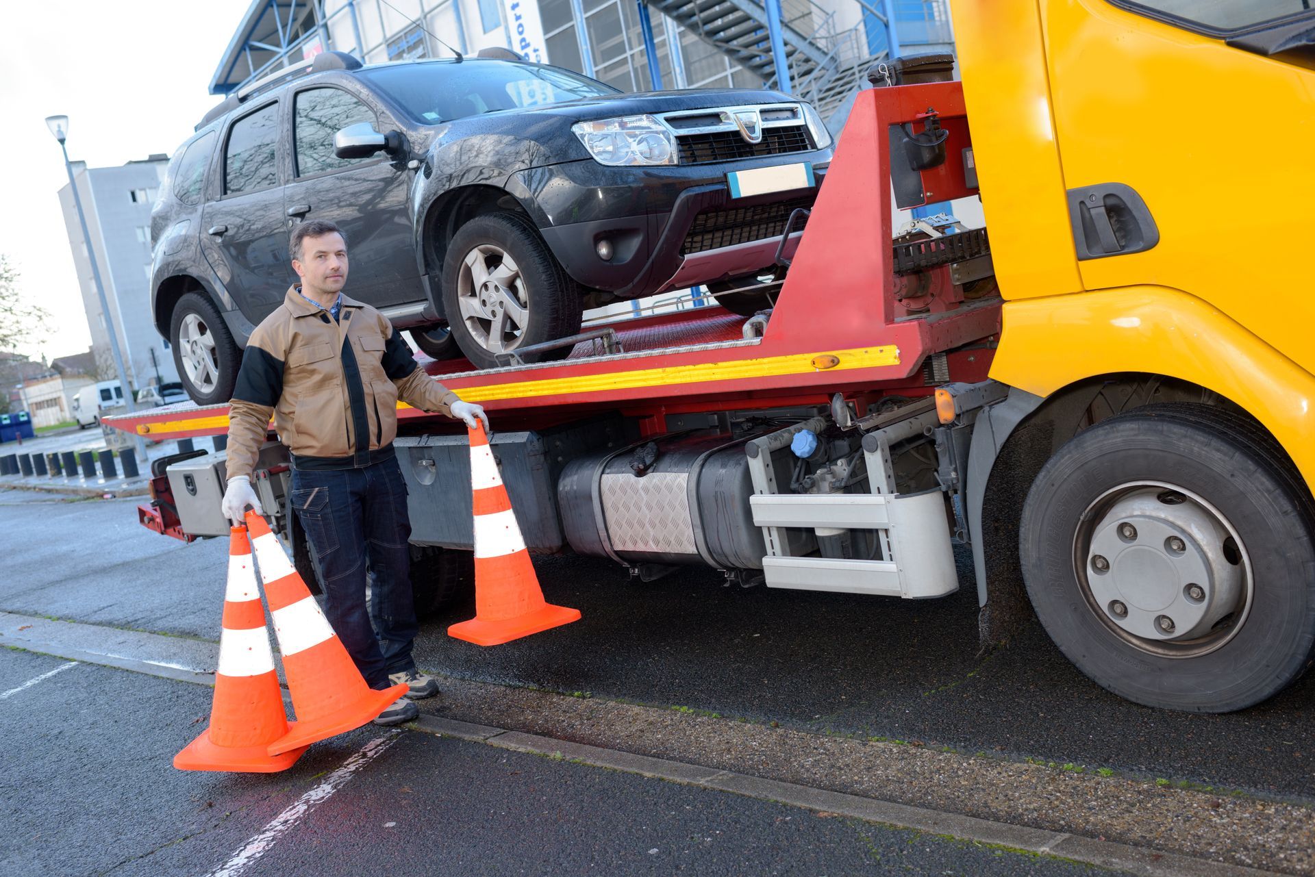 Tow truck operator with safety cones and a car on the truck bed. Tow truck operator with safety cones and a car on the truck bed.