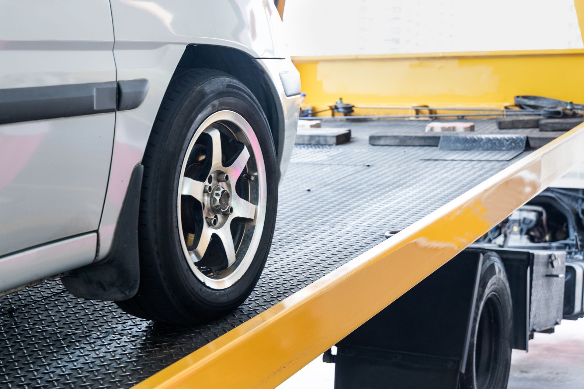 Car being loaded onto a yellow tow truck bed. Car being loaded onto a yellow tow truck bed.