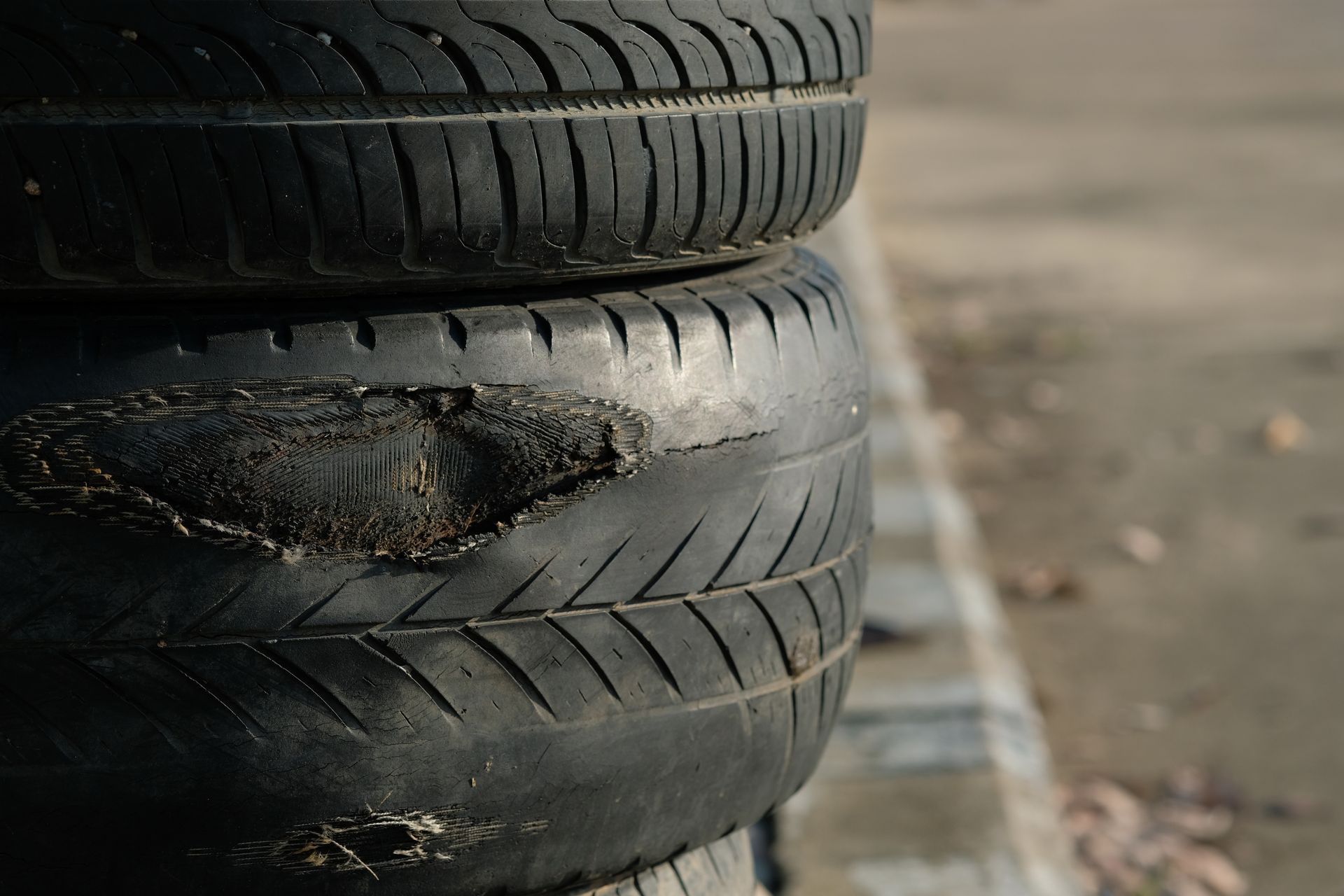 Stack of worn tires, one with significant damage. Stack of worn tires, one with significant damage.