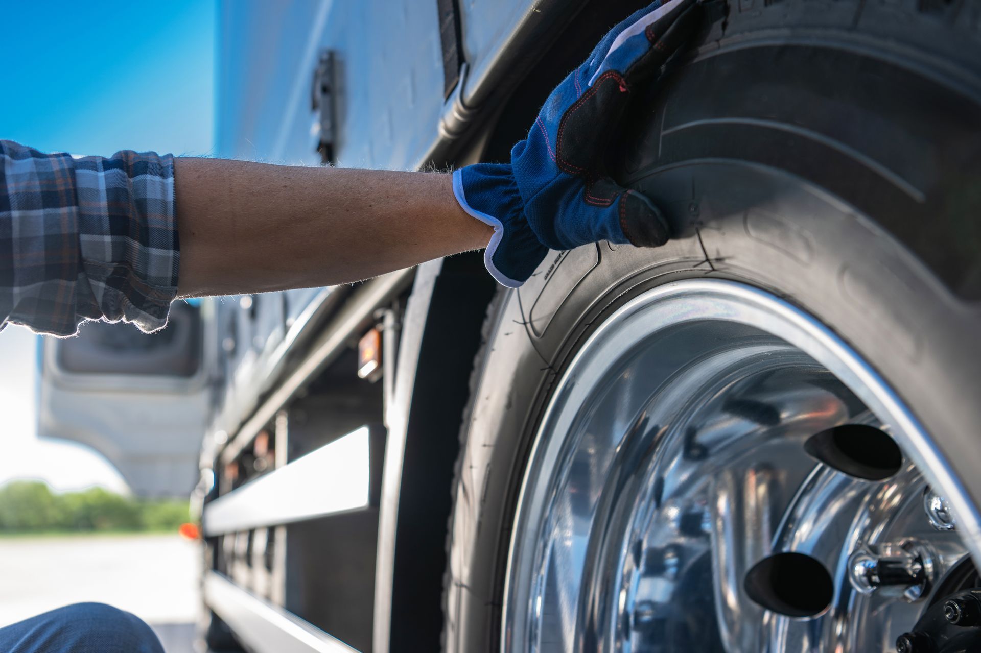 Person in blue gloves checking a semi-truck tire. Person in blue gloves checking a semi-truck tire.
