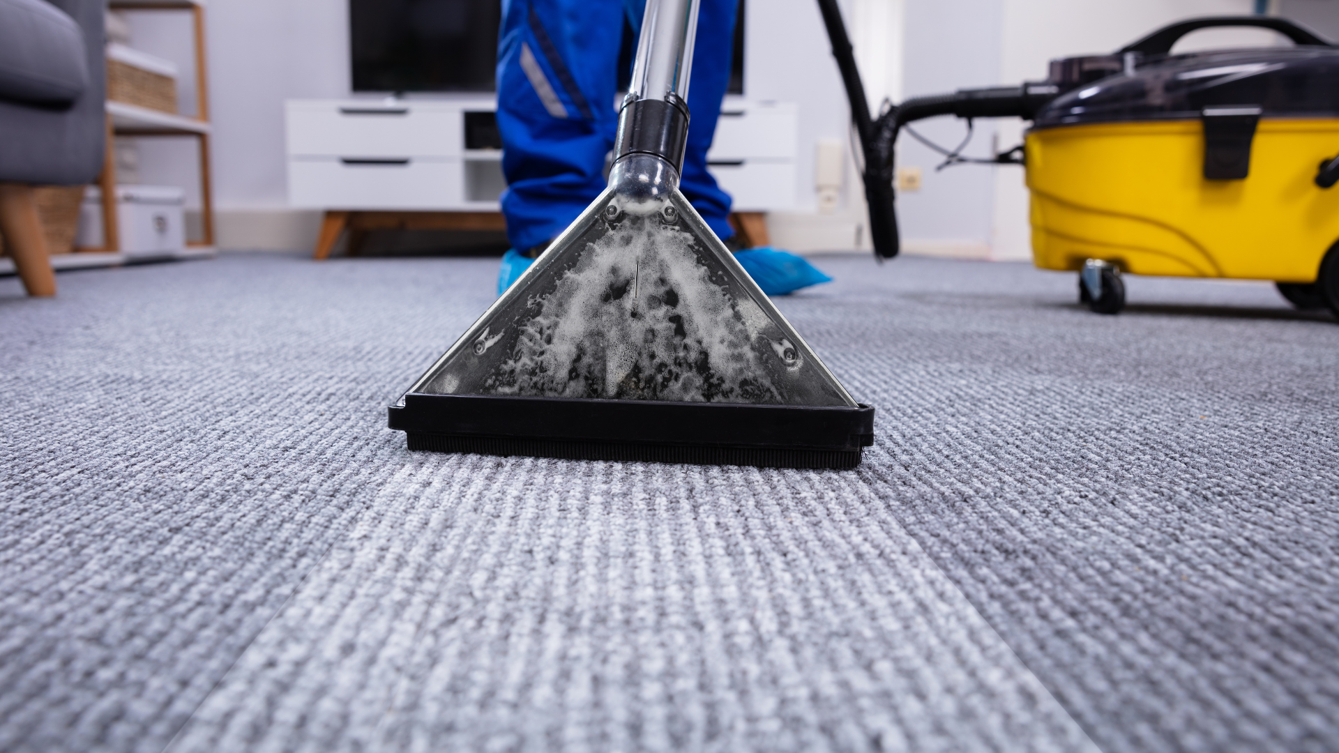 A person is cleaning a carpet with a vacuum cleaner.
