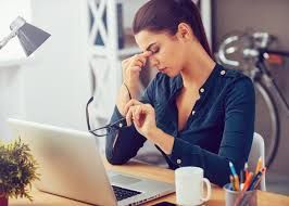 A woman is sitting at a desk in front of a laptop computer.
