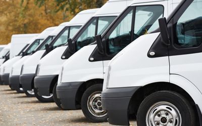 A row of white vans parked next to each other in a parking lot.