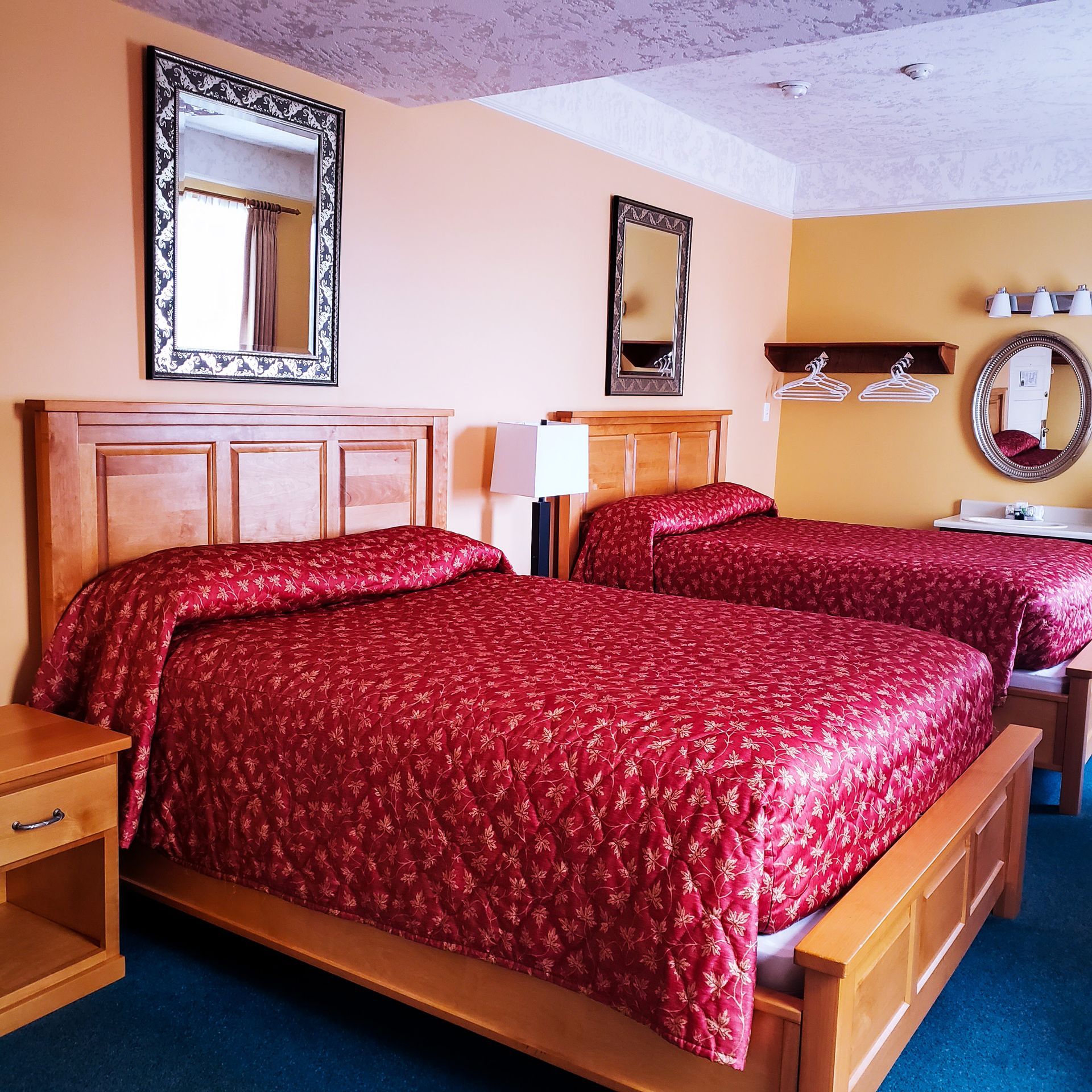A hotel room with two beds and two mirrors