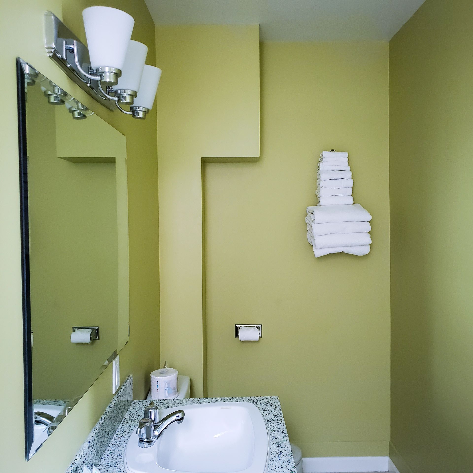 A bathroom with a sink a mirror and a stack of towels