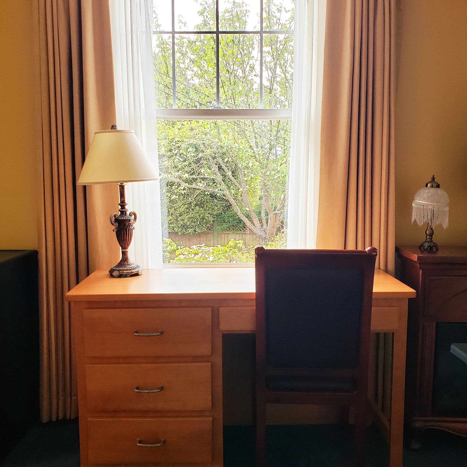 A desk with a lamp and a chair in front of a window