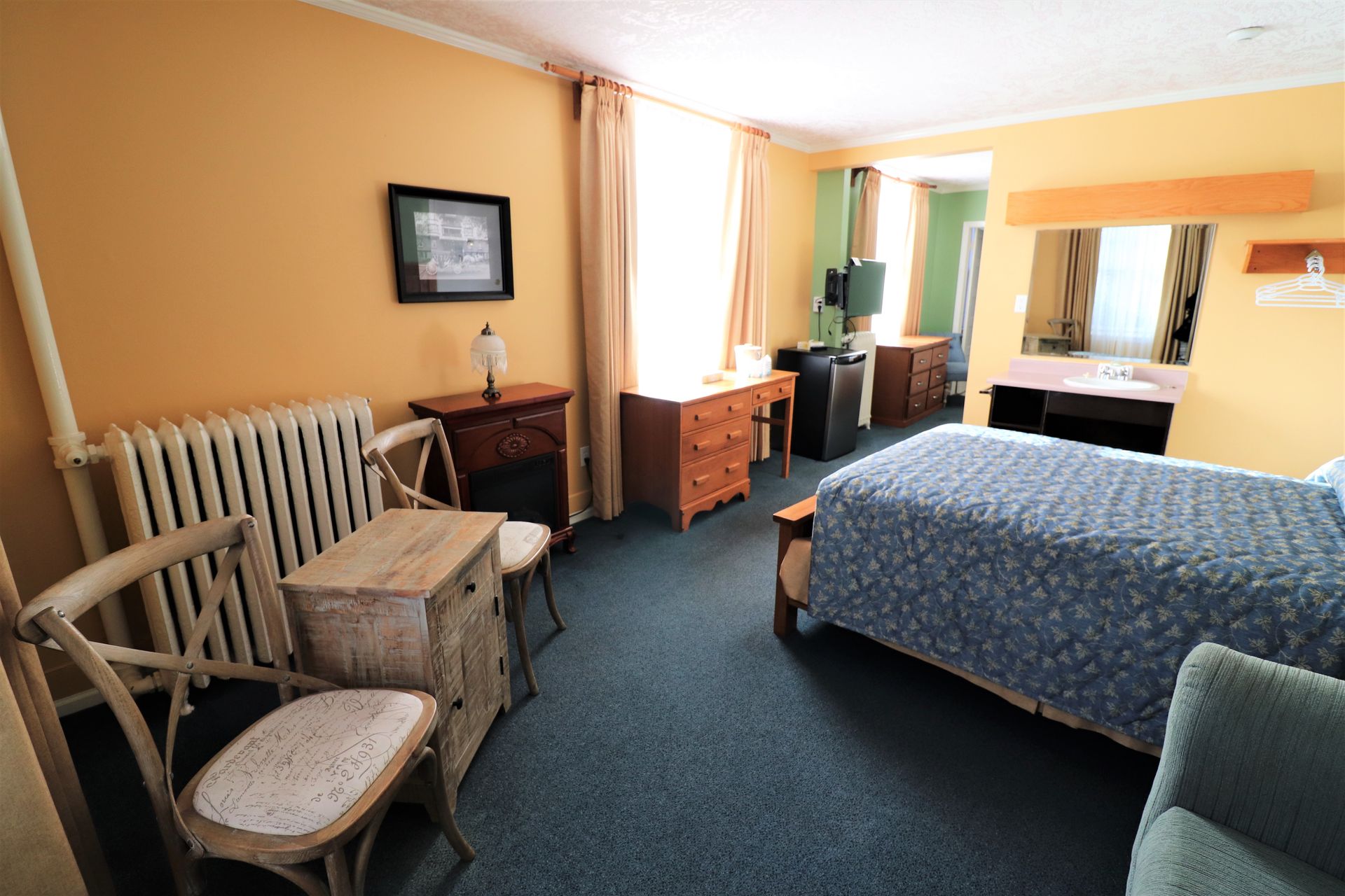 A hotel room with a bed , chairs and a radiator