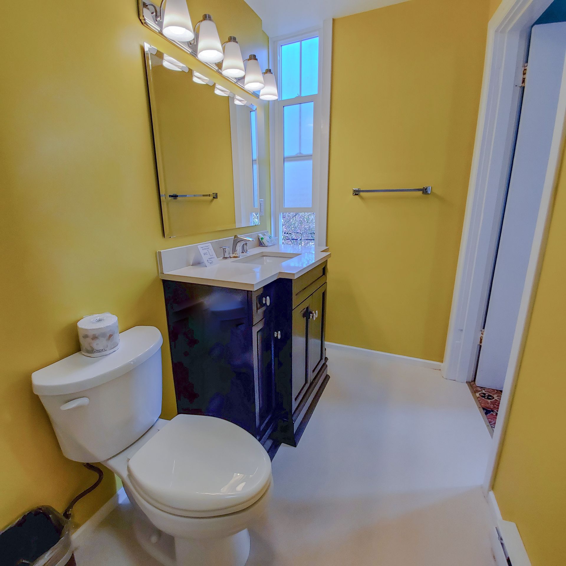 A bathroom with yellow walls and a toilet and sink
