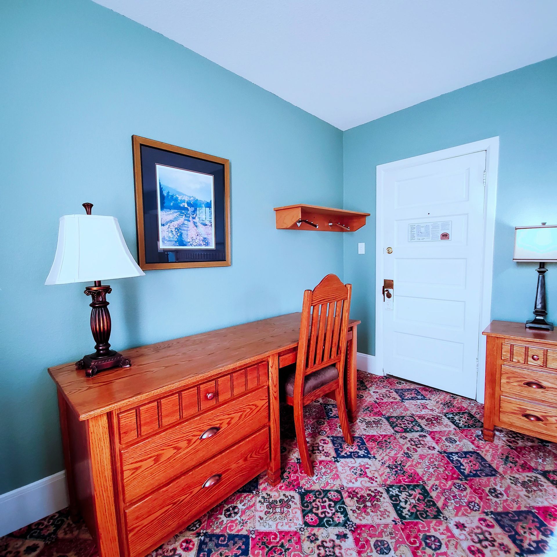 A room with a desk and chair and a picture on the wall