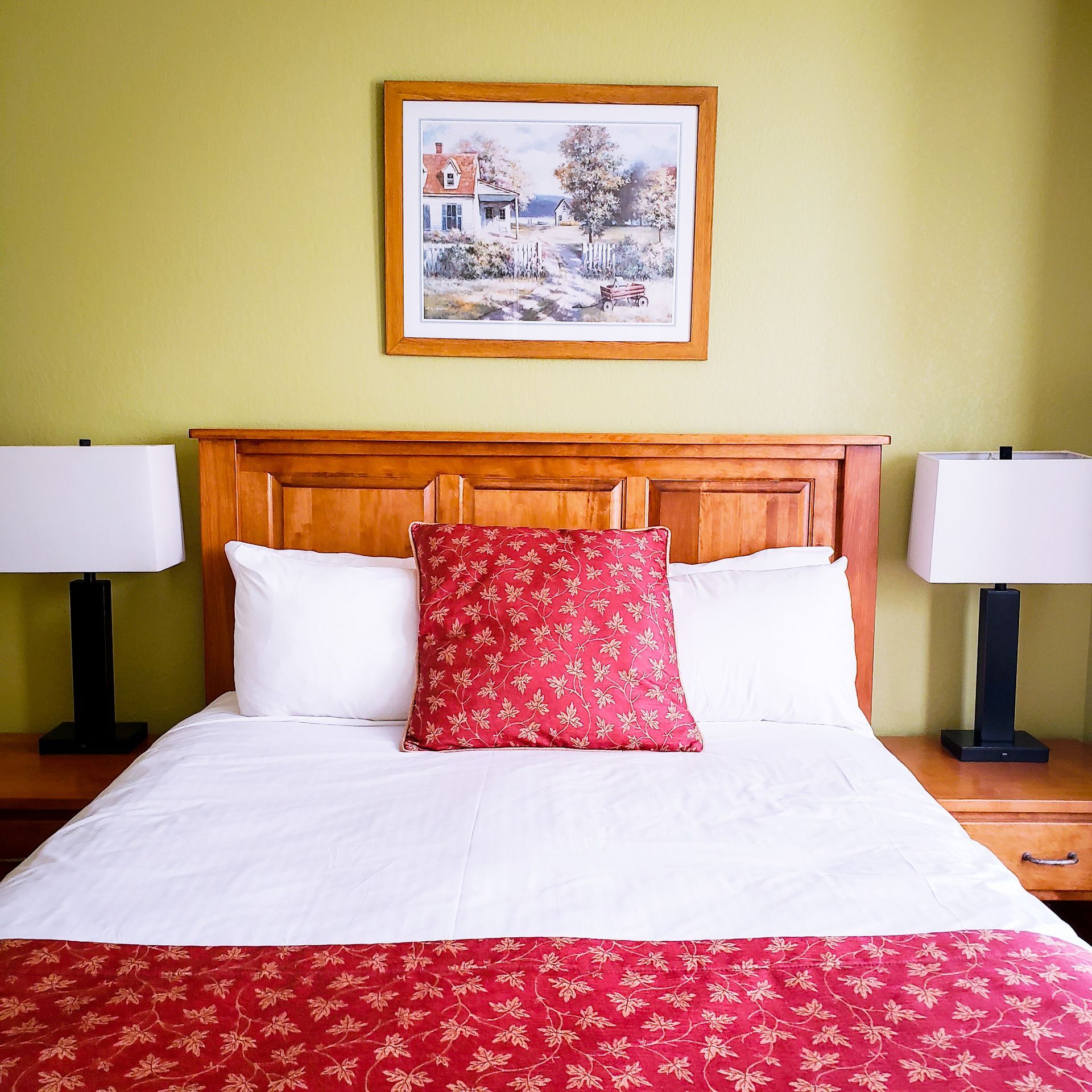 A bed with a picture on the wall above it