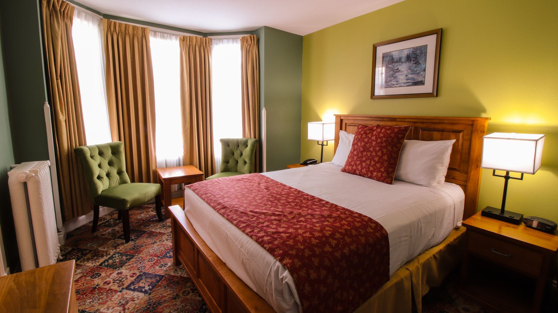 A hotel room with a king size bed and green chairs