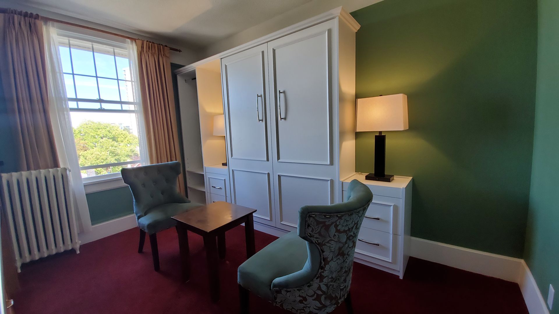 A living room with two chairs , a table and a lamp.
