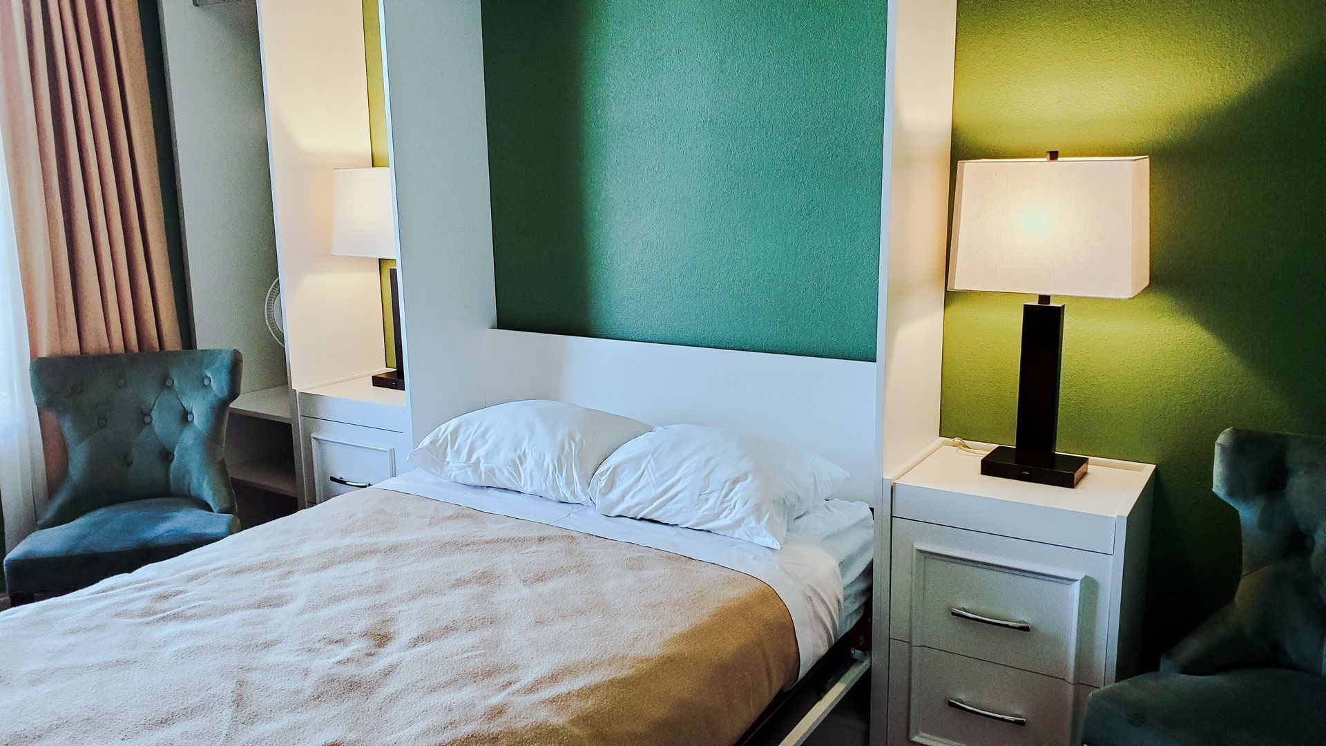 A hotel room with a bed , chair , nightstand and lamp.