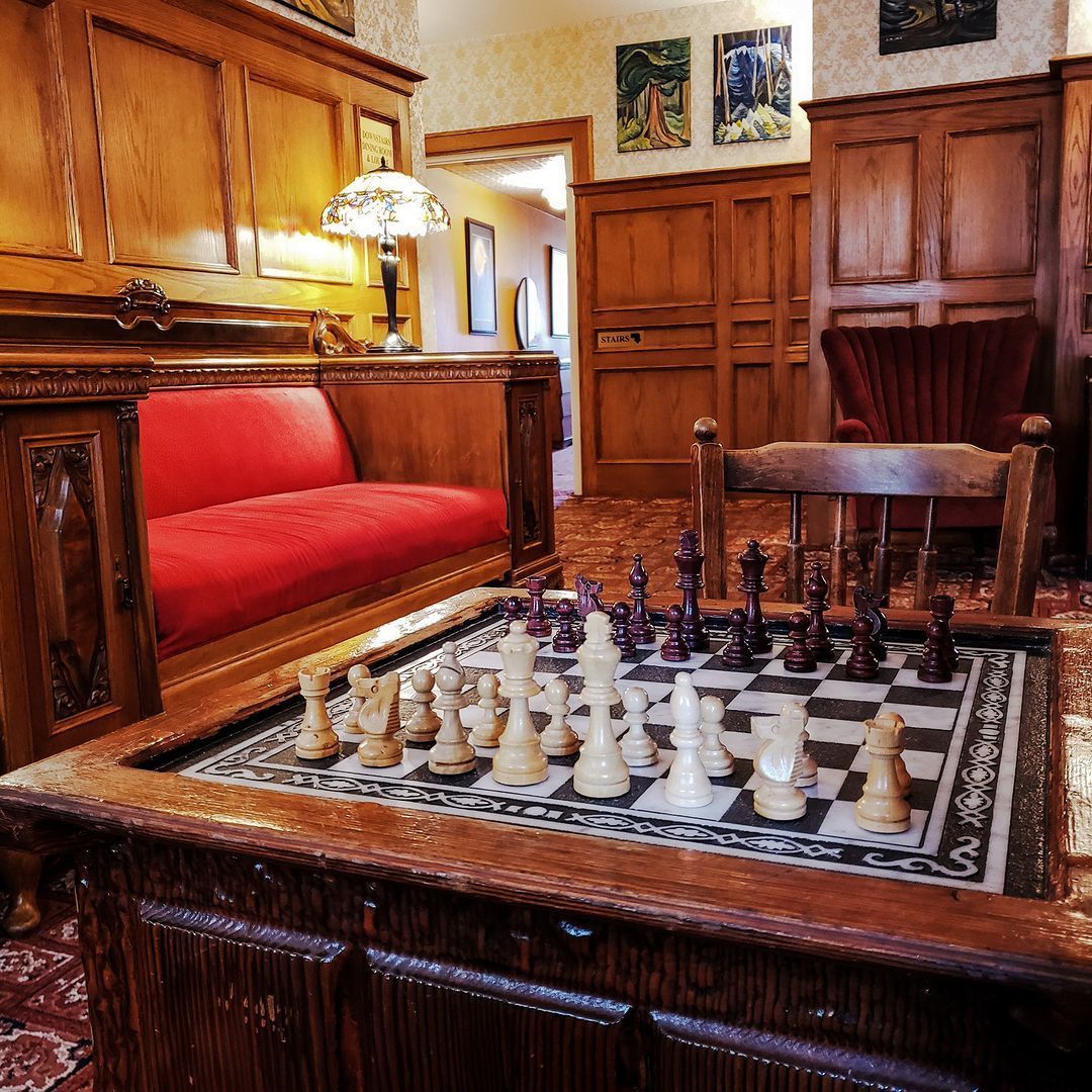 A chess board is on a wooden table in a living room.