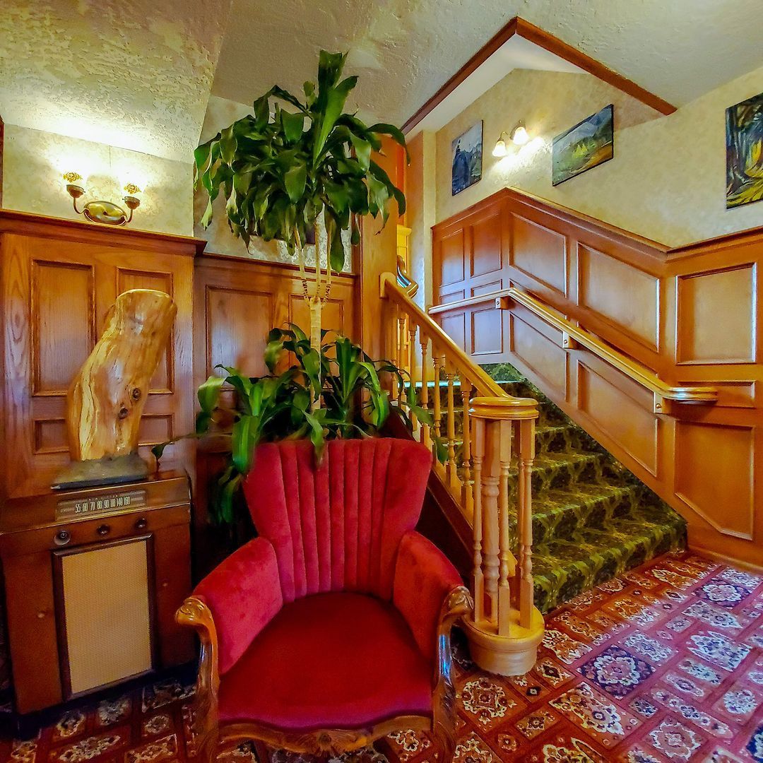 A red chair in a room with stairs and a plant