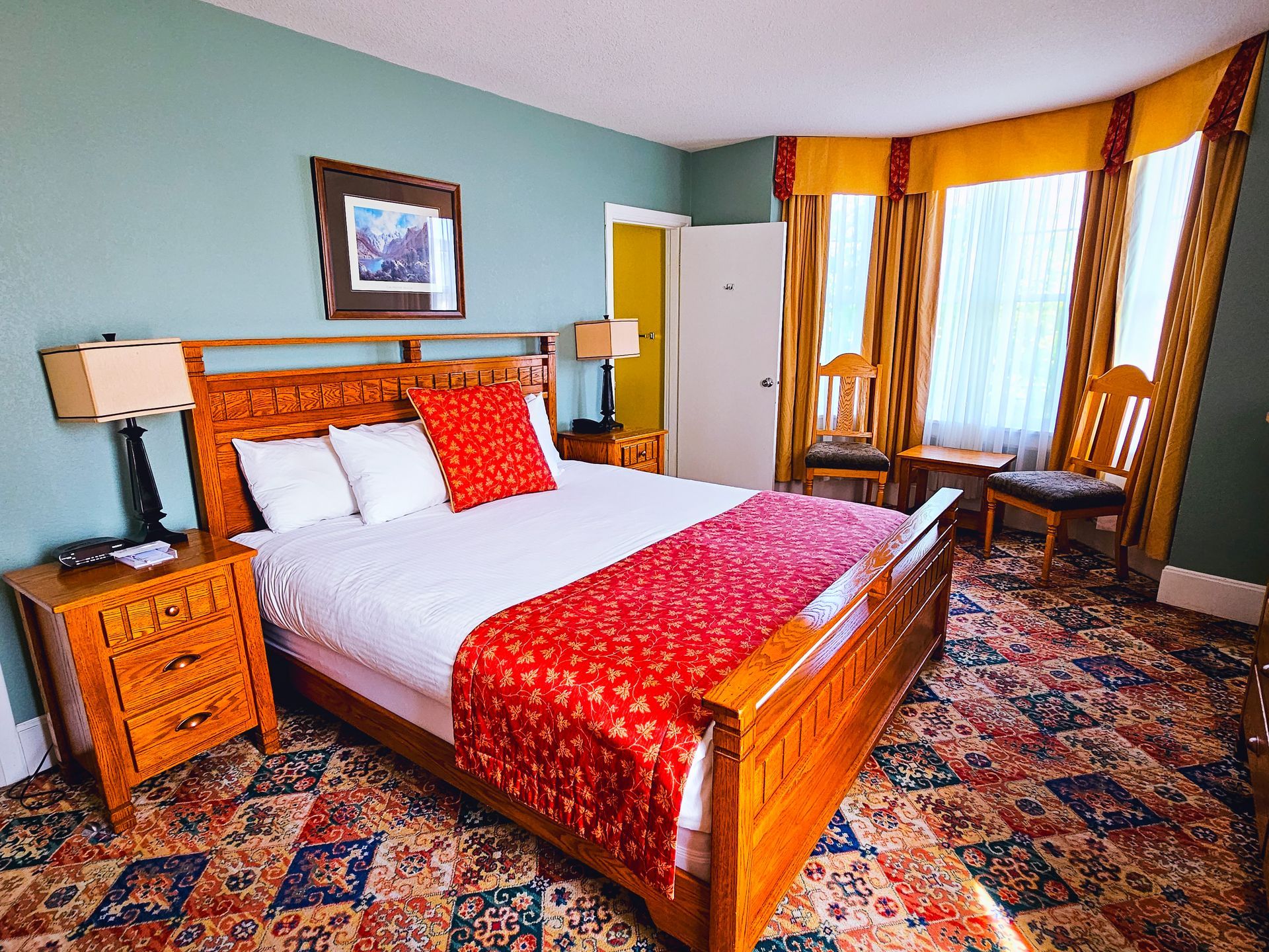 A hotel room with a king size bed , nightstands , lamps and chairs.
