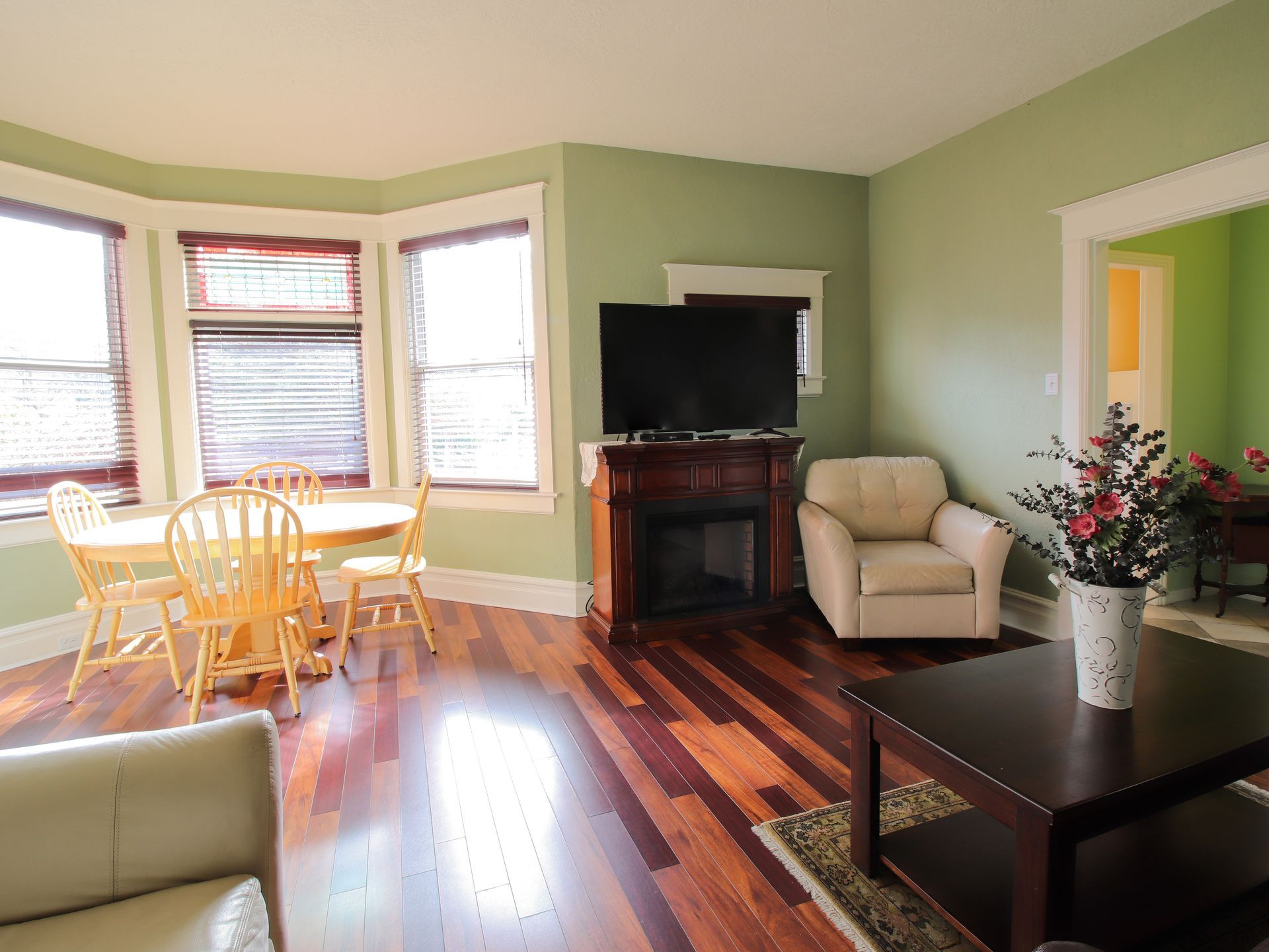 A living room with hardwood floors , a fireplace , a table and chairs.