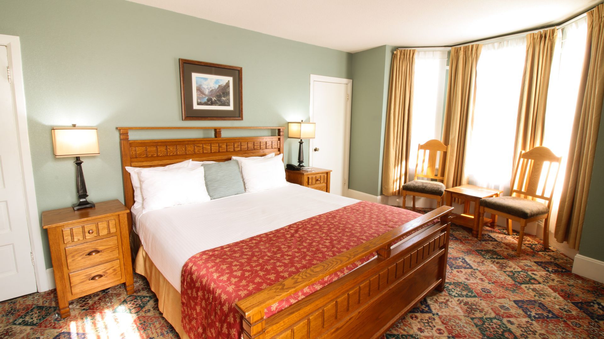 A hotel room with a king size bed and two chairs