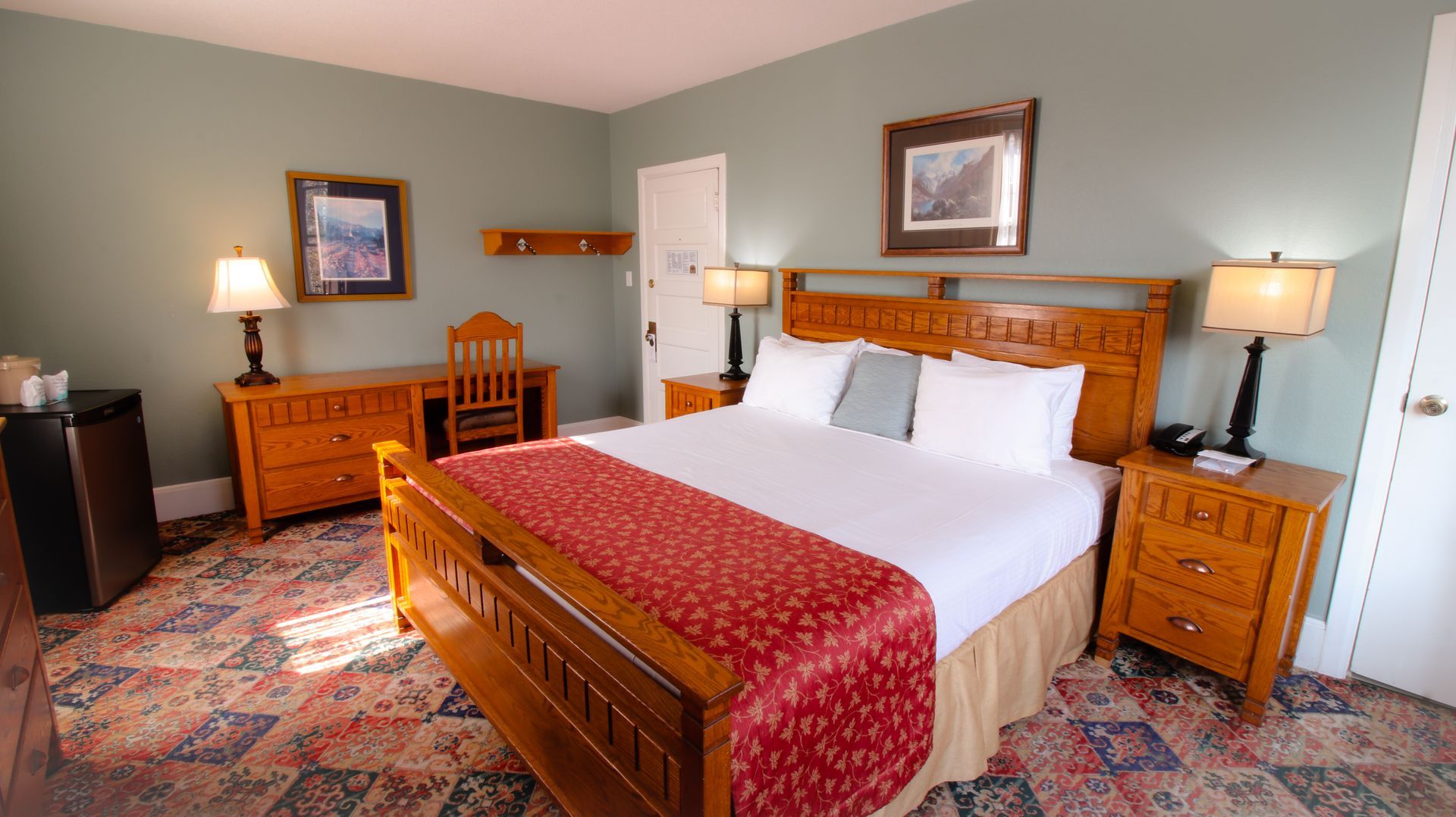 A hotel room with a king size bed and a desk.
