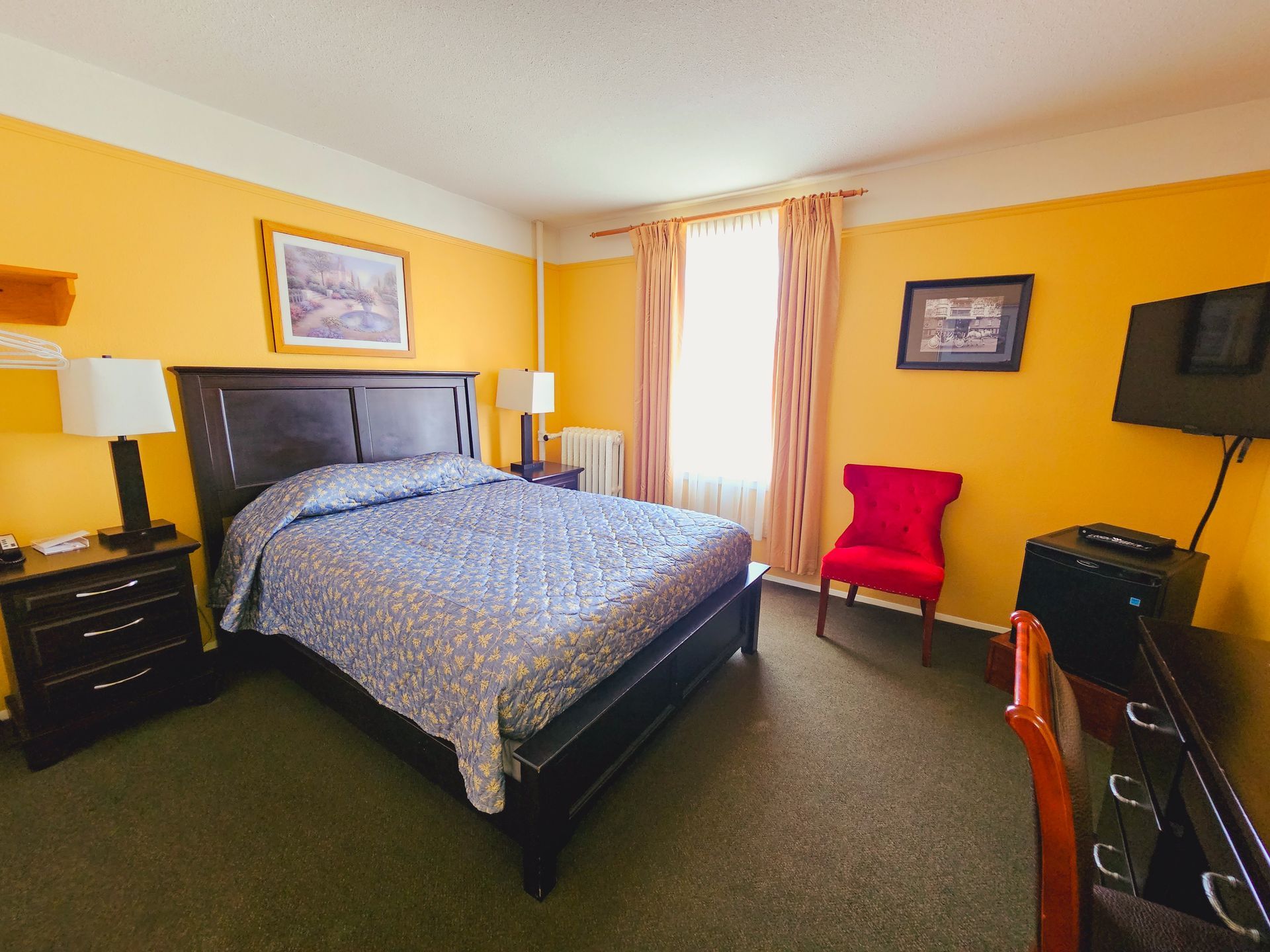A hotel room with a king size bed and a red chair