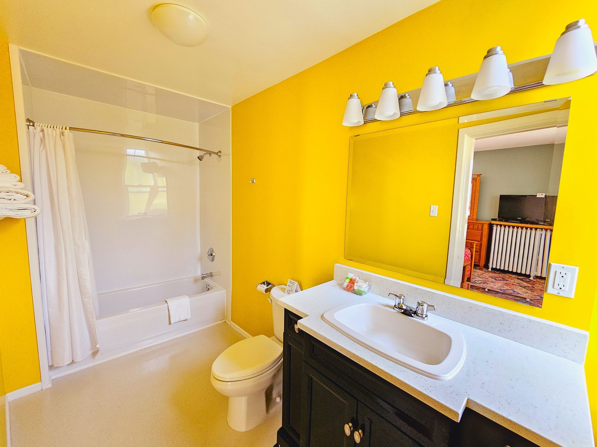 A bathroom with yellow walls , a sink , toilet and bathtub.