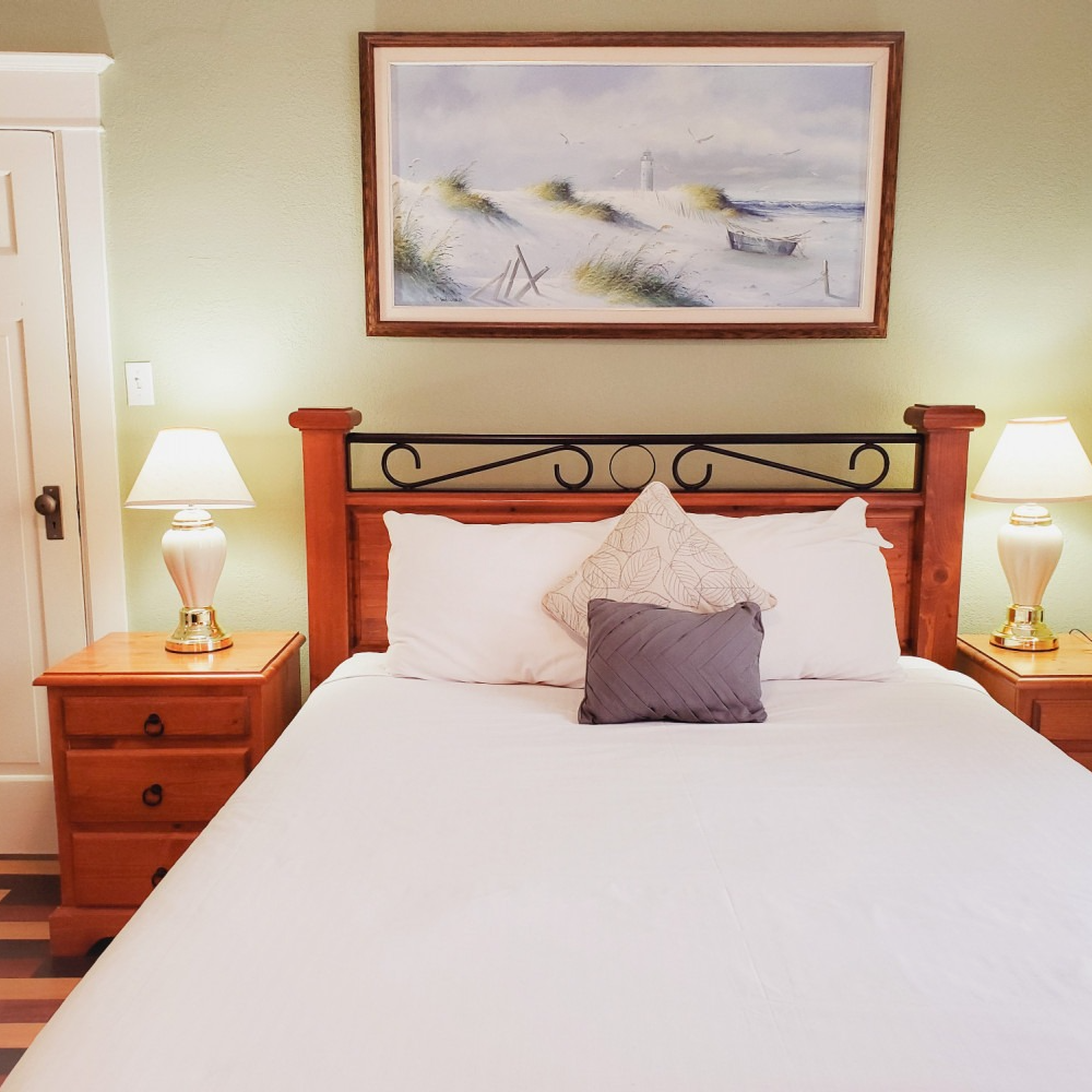 A bedroom with a painting on the wall above the bed
