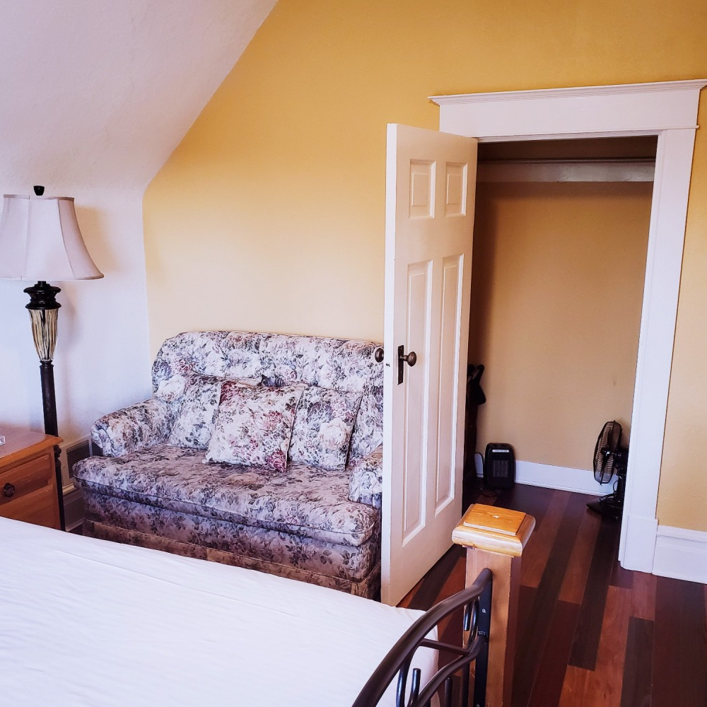 A bedroom with a couch and a lamp in it