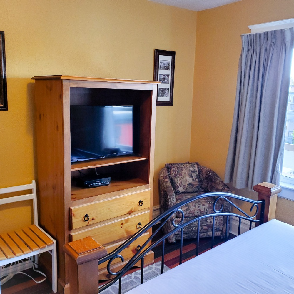 A bedroom with a bed a chair and a television