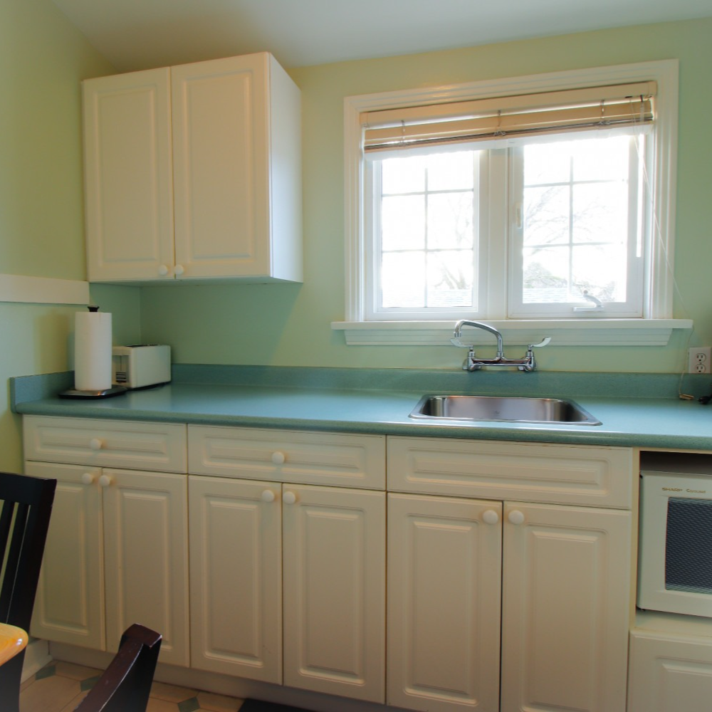 A kitchen with white cabinets a sink and a window