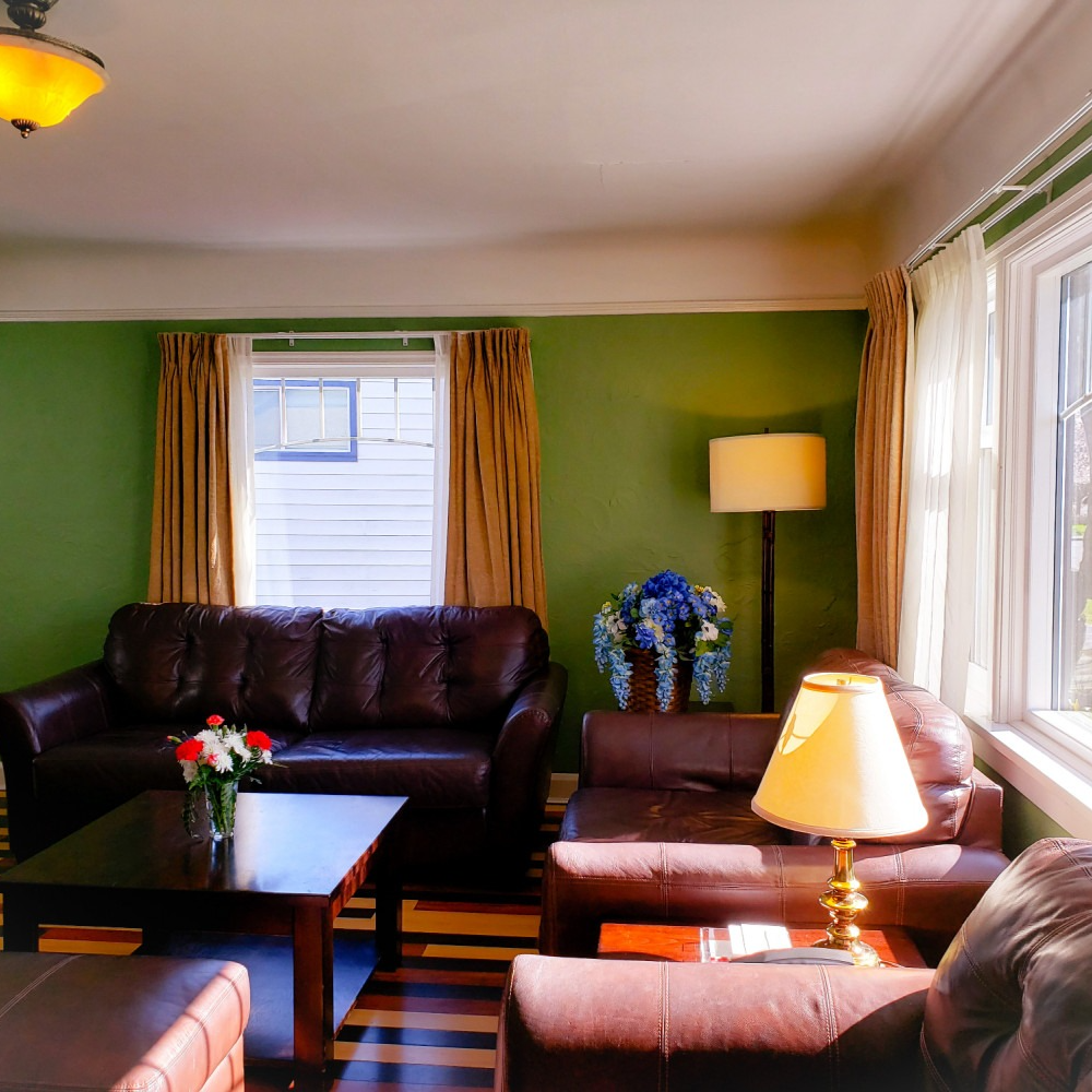 A living room with green walls and brown furniture
