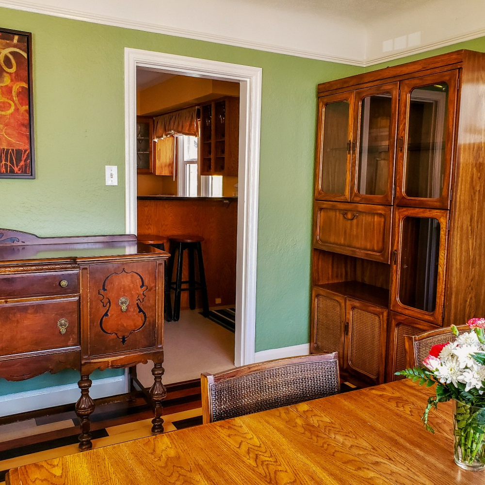 A dining room with a table and chairs and a dresser