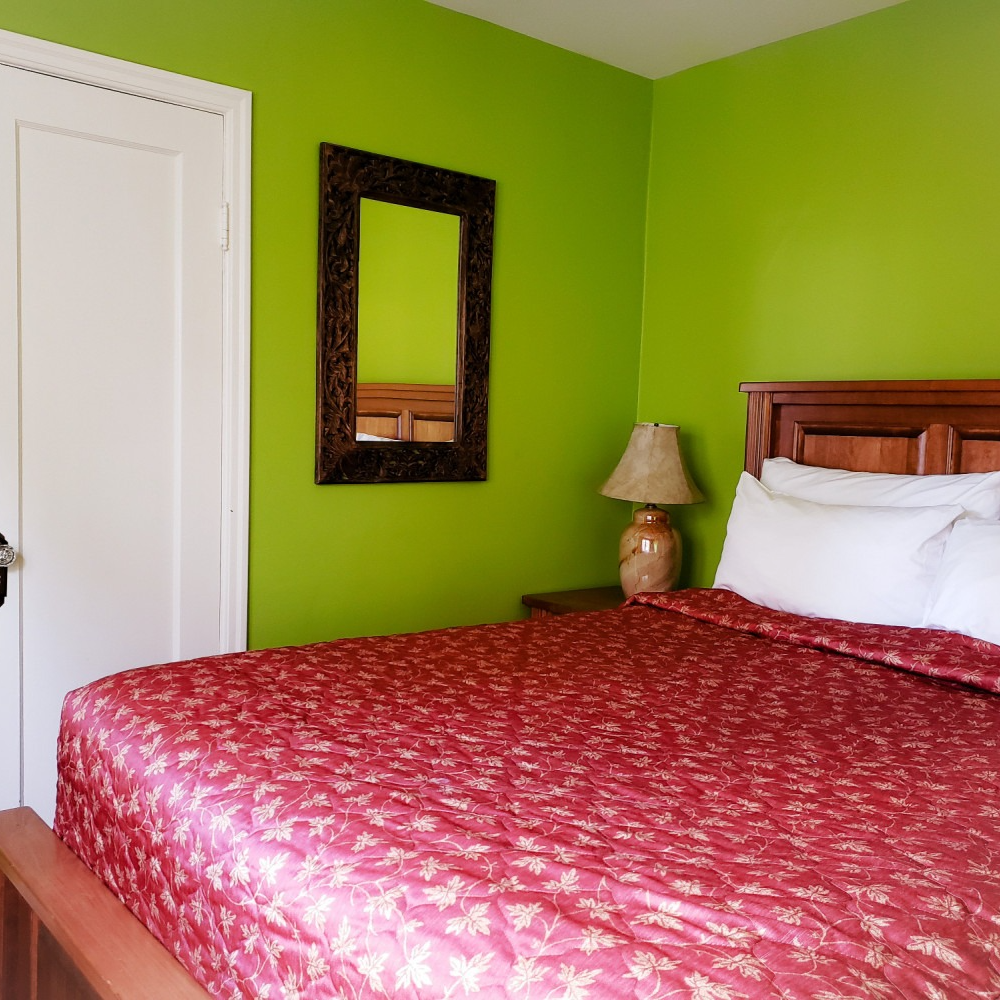 A bedroom with green walls and a red bed