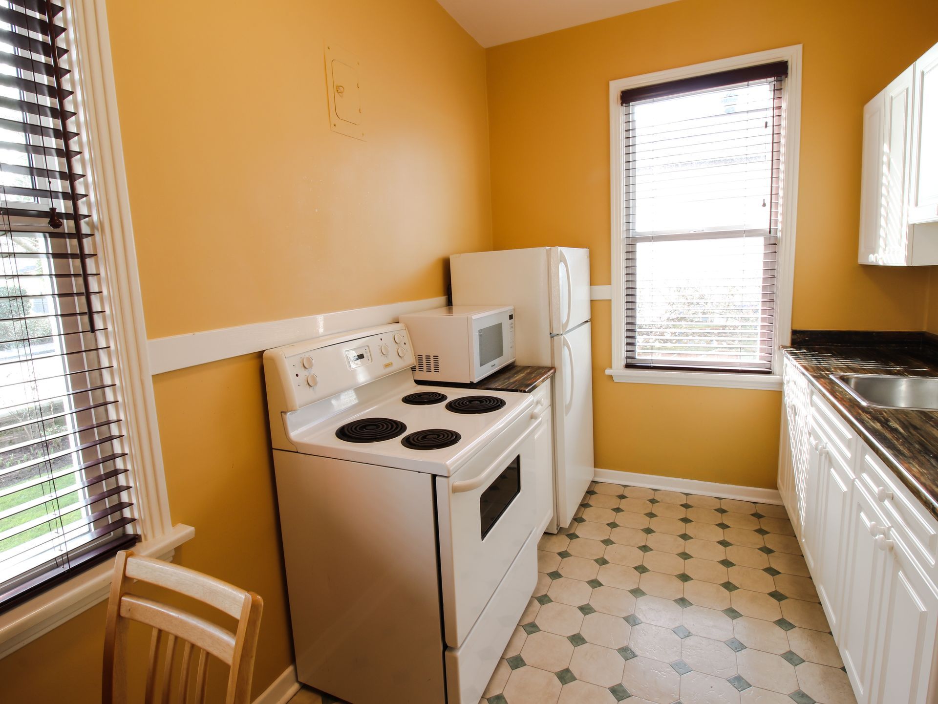 A kitchen with a stove a refrigerator and a microwave