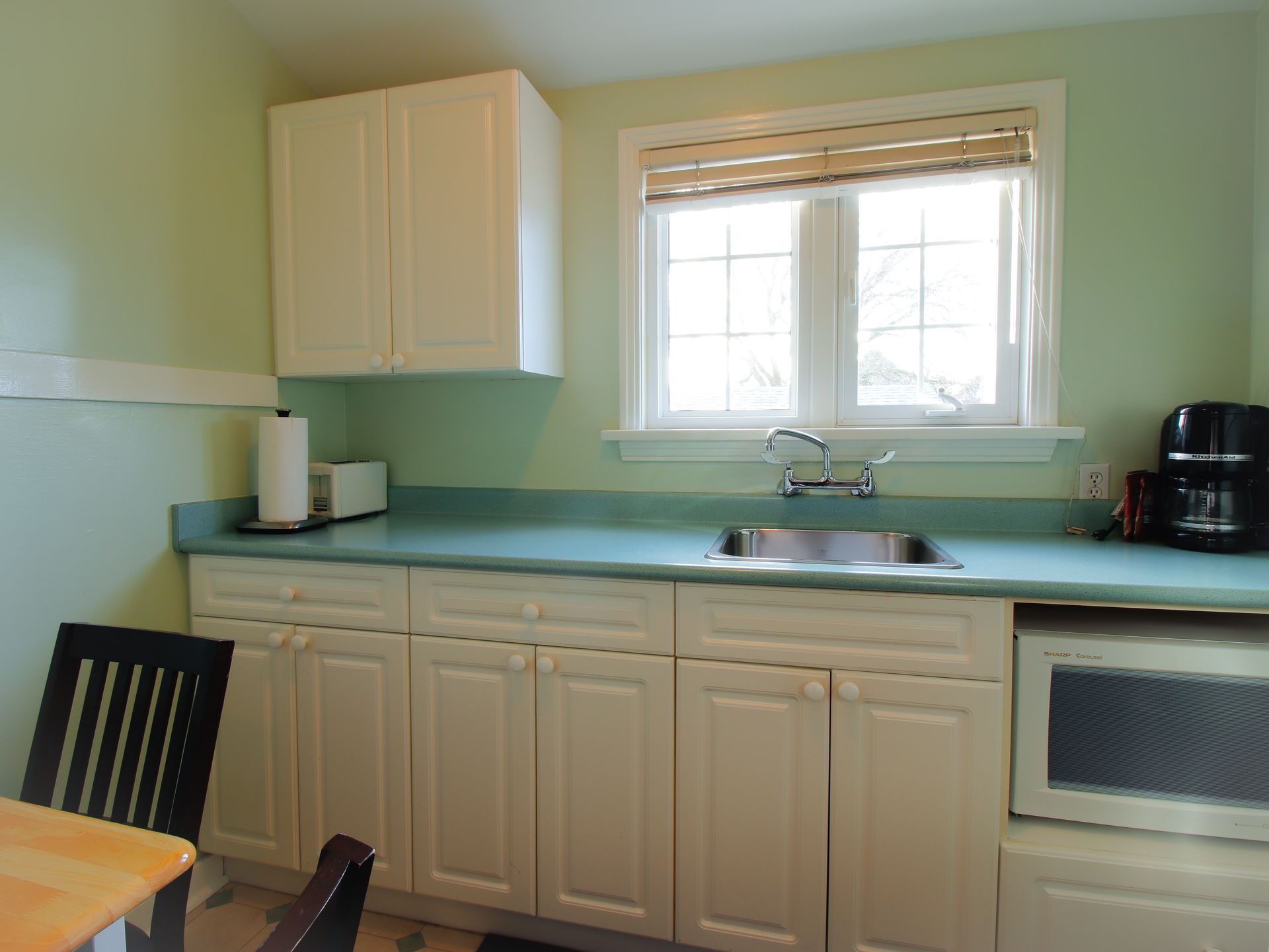 A kitchen with white cabinets a sink and a microwave