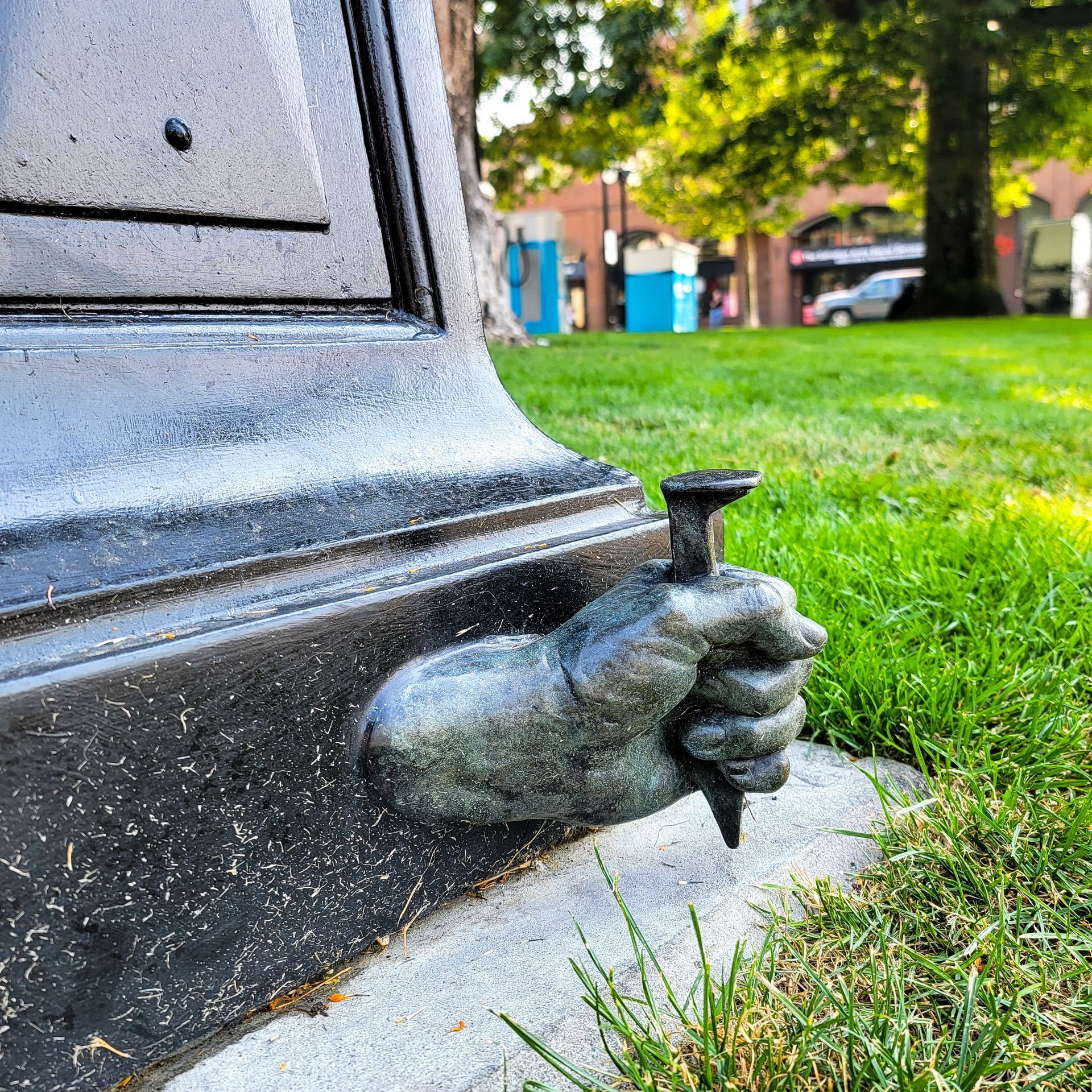 A statue of a hand holding a nail in the grass.