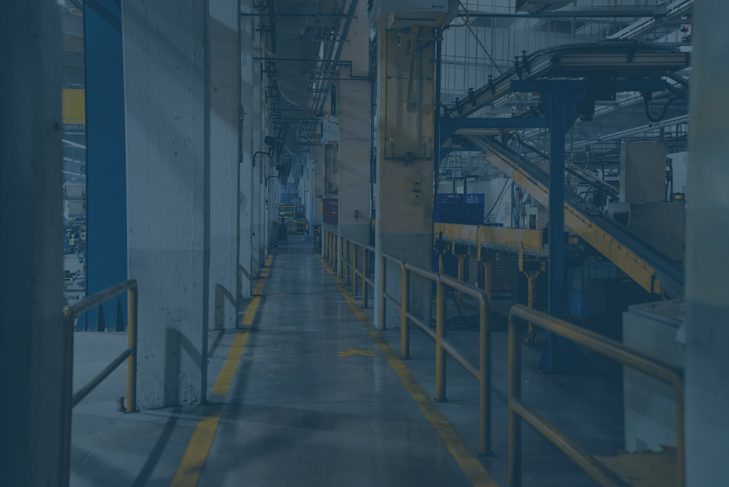 Industrial hallway with yellow lines, metal railings, and machinery.
