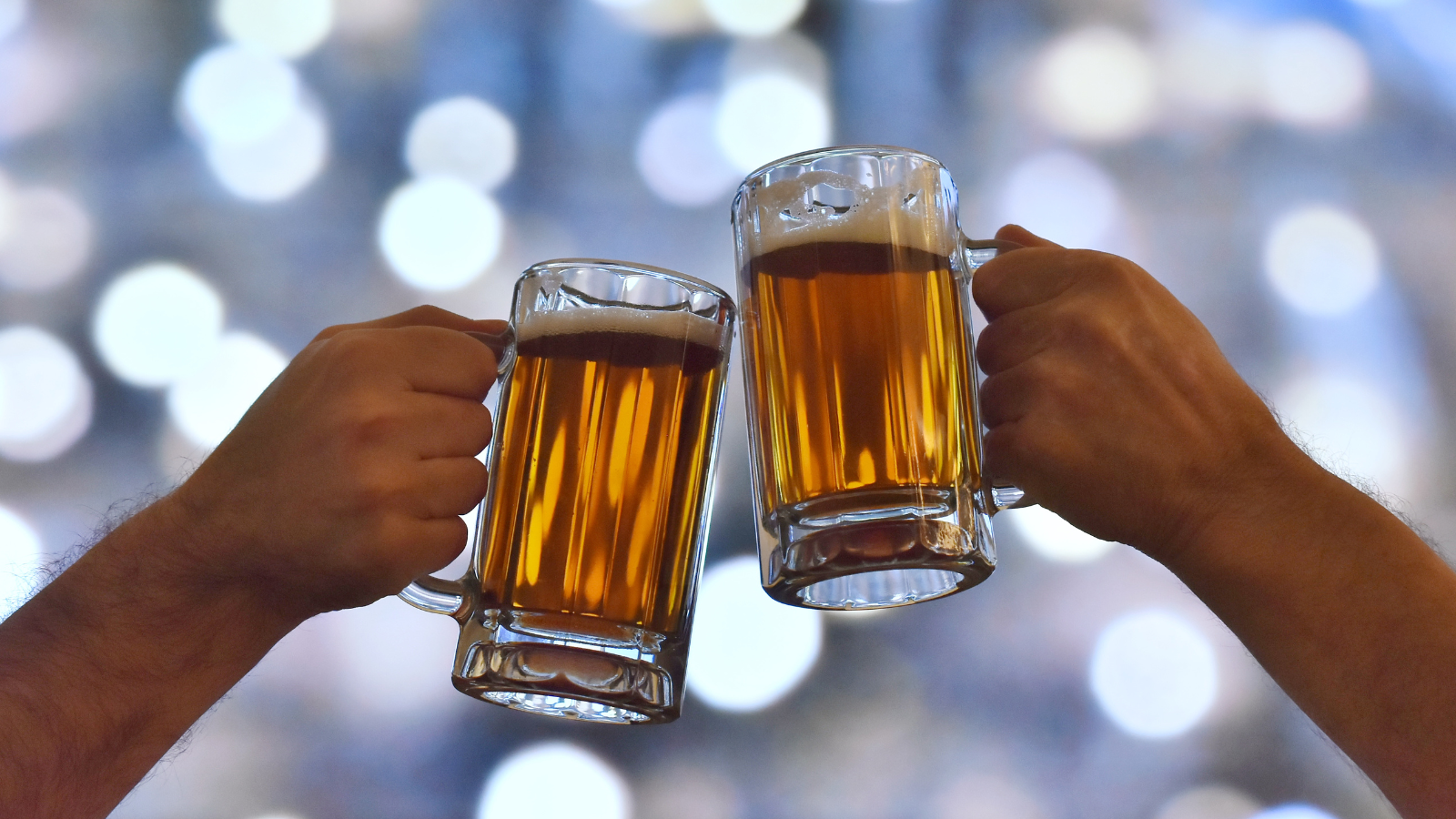 Two beers in much cheering in front of bright white lights in winter