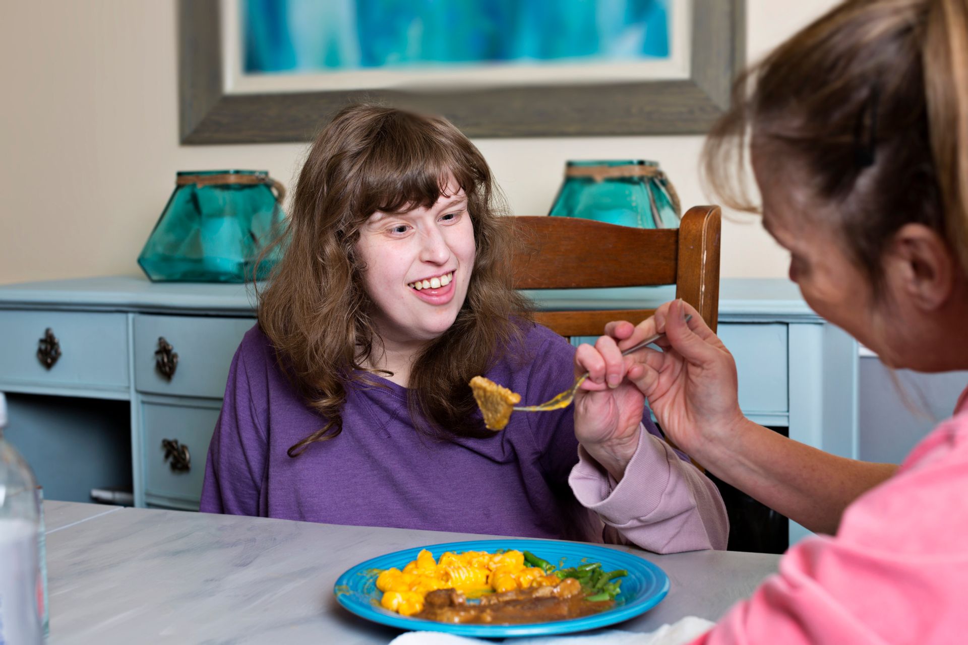 A woman is feeding a woman with a spoon from a plate of food.