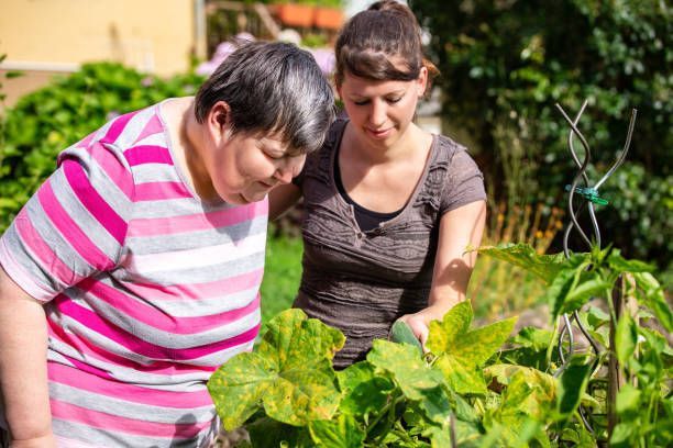 Two women are looking at plants in a garden.